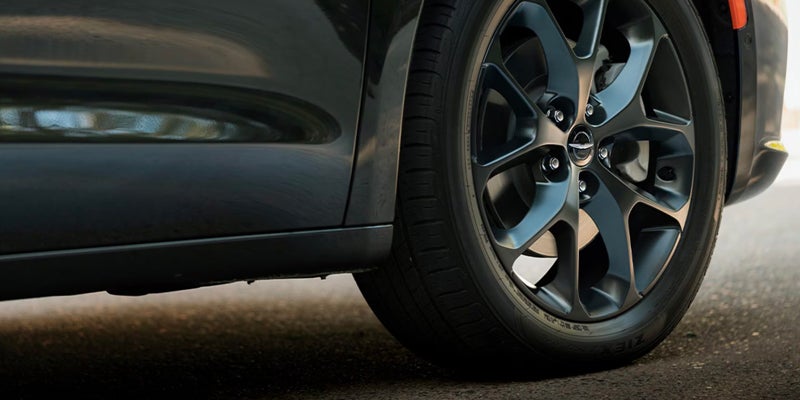 Close-up view of a Chrysler Pacifica alloy wheel and tire alongside the lower side body panel.