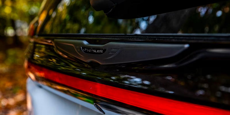 Rear view detail of a Chrysler Pacifica featuring a full-width LED taillight strip and Chrysler badge.