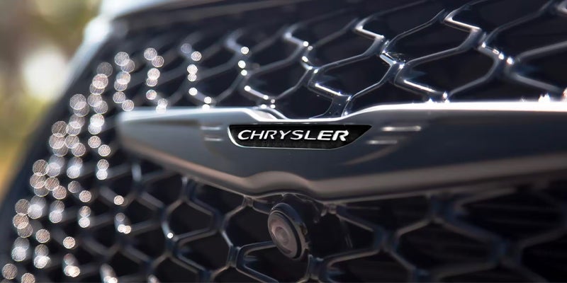 Close-up of the Chrysler Pacifica front grille with a honeycomb mesh design and Chrysler emblem at the center.