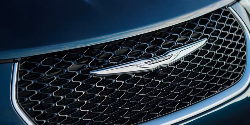 Close-up of the Chrysler Pacifica front grille featuring the Chrysler winged emblem and black mesh grille design
