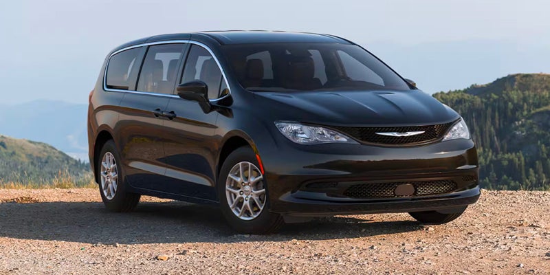 Black Chrysler minivan parked outdoors, shown from a front three-quarter angle with hills and open landscape in the background.