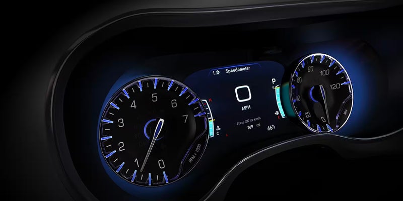 Close-up of the Chrysler digital instrument cluster displaying vehicle speed, fuel information, and driver assistance indicators with blue accents