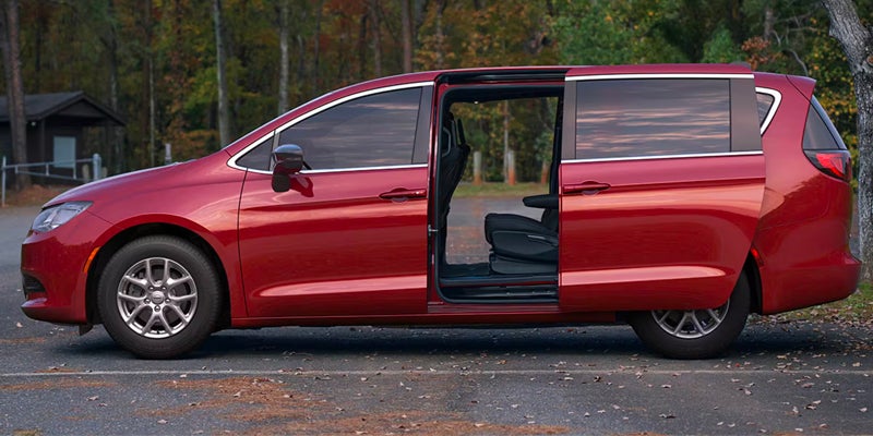 Red Chrysler minivan parked with the passenger-side sliding door open, showcasing easy access to the interior seating area