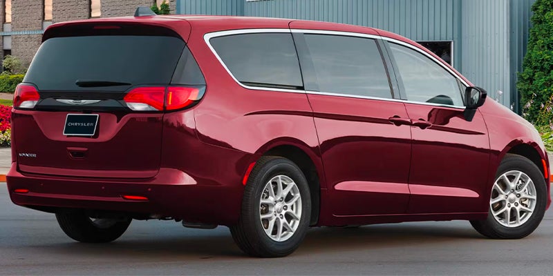 Red Chrysler minivan shown from a rear three-quarter angle, highlighting the side profile, rear hatch, and taillights.
