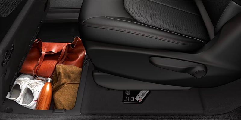 Close-up of a Chrysler minivan interior showing a storage compartment beneath a seat containing personal belongings and travel items