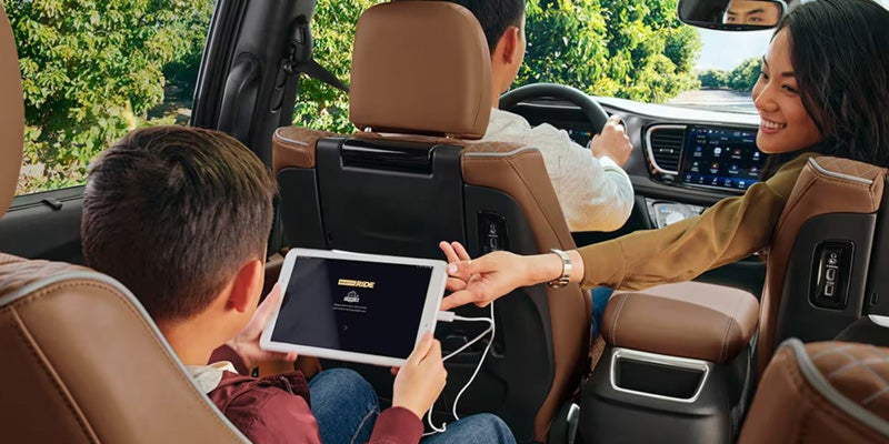 Chrysler Pacifica cabin with rear-seat passengers using a tablet device while seated behind the front seats