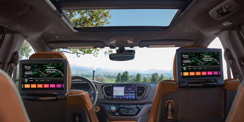 Interior view of a Chrysler Pacifica featuring rear-seat entertainment screens mounted behind the front seats and a panoramic sunroof above