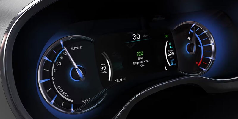 Digital instrument cluster in a Chrysler Pacifica displaying vehicle speed, hybrid performance data, battery status, and driving information