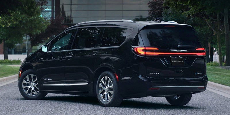 Black Chrysler Pacifica minivan viewed from the rear three-quarter angle on a city street, highlighting exterior styling and LED taillights.