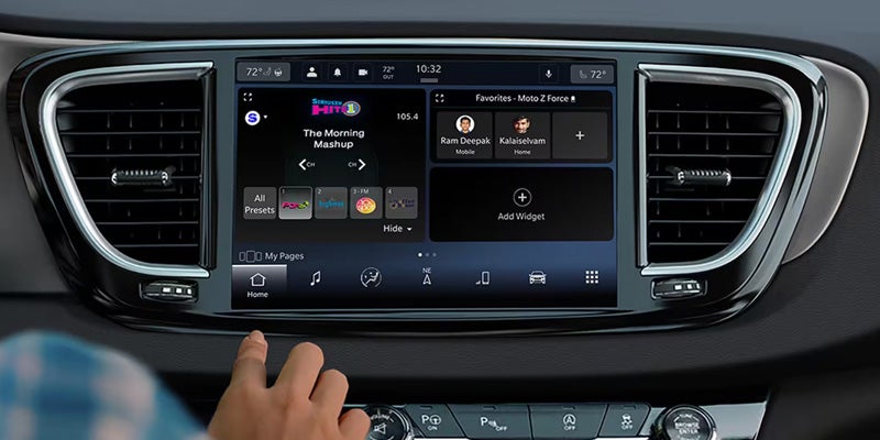 Chrysler infotainment touchscreen displaying media, navigation, and vehicle features, with a hand interacting with the digital interface.
