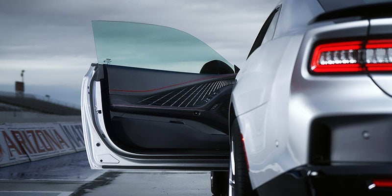 Open door of a white Dodge Charger Daytona showing detailed interior door trim, speaker grille