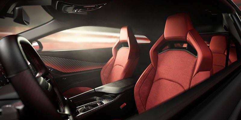 Front cabin of a Dodge Charger Daytona featuring red sport seats, a center console, and premium interior trim.