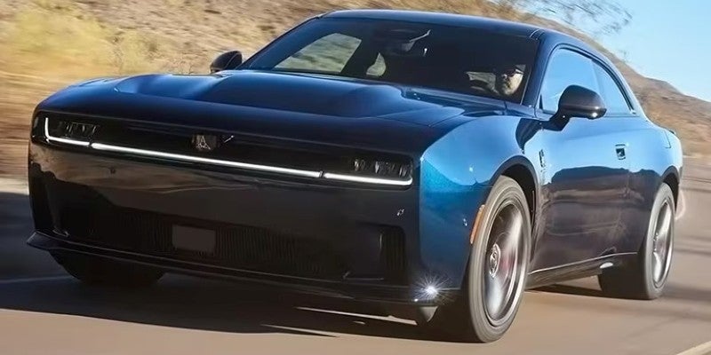 Blue Dodge Charger Daytona driving on an open road, shown from a low front three-quarter angle