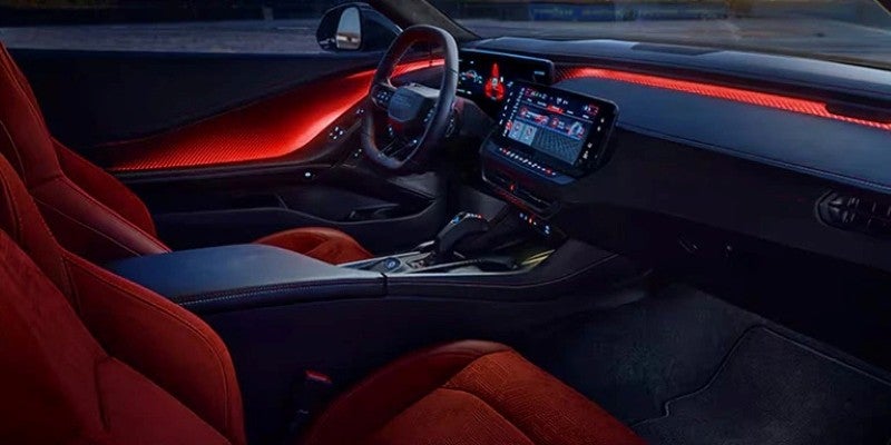 Interior of a Dodge Charger Daytona showcasing red sport seats, ambient lighting, a digital instrument cluster