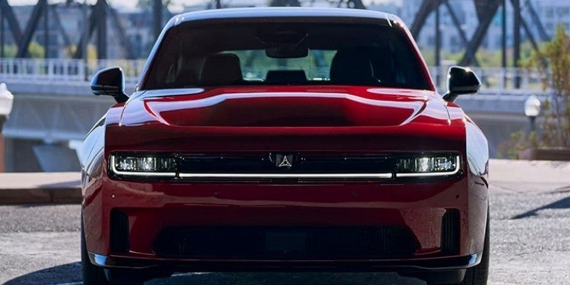 Red Dodge Charger Daytona viewed from the front, featuring a wide grille, sleek LED lighting,