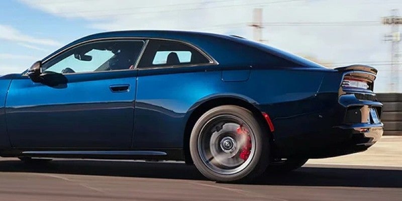 Blue Dodge Charger Daytona shown in motion from the side, highlighting its fastback roofline