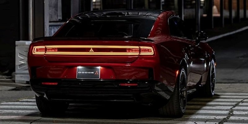 Rear view of a red Dodge Charger Daytona parked at night, featuring a full-width LED taillight