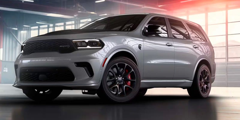 Silver Dodge Durango SRT Hellcat parked indoors, showcasing its aggressive styling, black wheels, and red brake calipers