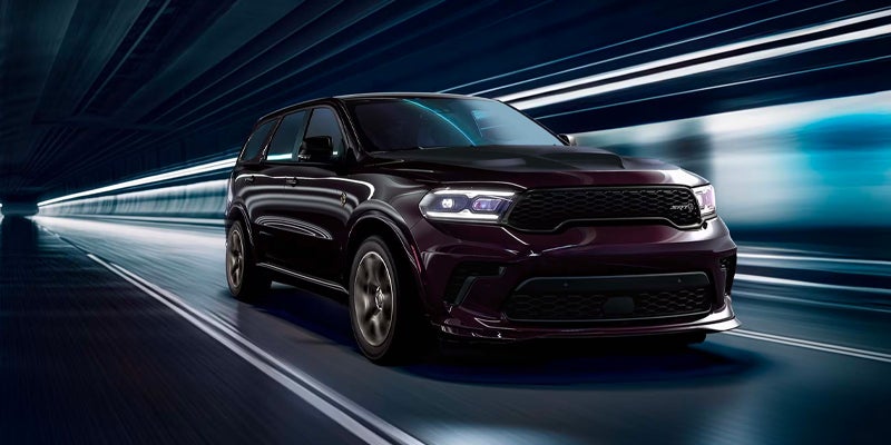 Dark-colored Dodge Durango SRT driving through a brightly lit tunnel, highlighting its performance-focused front fascia