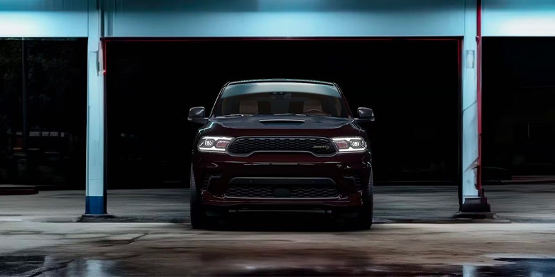 Front view of a Dodge Durango SRT parked inside an industrial-style garage with illuminated overhead lighting