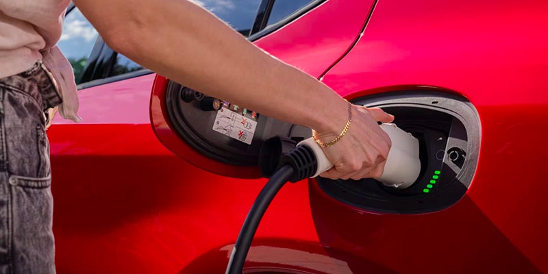 Close-up of a Dodge Hornet plug-in hybrid charging port with a charging cable connected.
