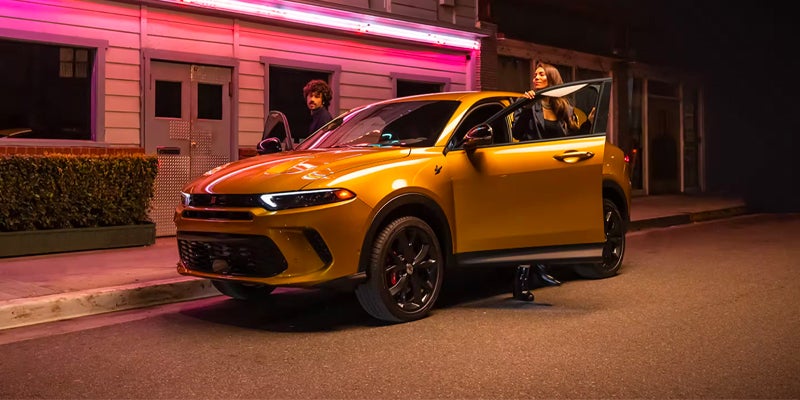 Gold Dodge Hornet parked outside a building at night with illuminated exterior lighting