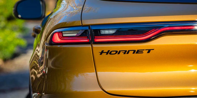 Close-up of the rear taillight and Hornet badge on a gold Dodge Hornet, highlighting the LED light design.