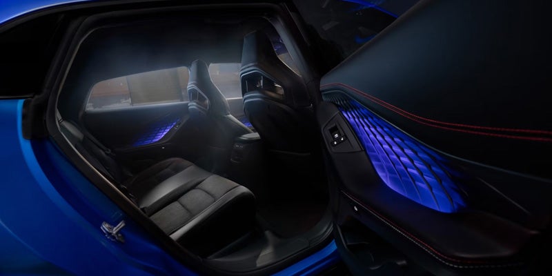 Rear passenger compartment of a Dodge Charger Daytona with black leather seats and blue ambient interior lighting.