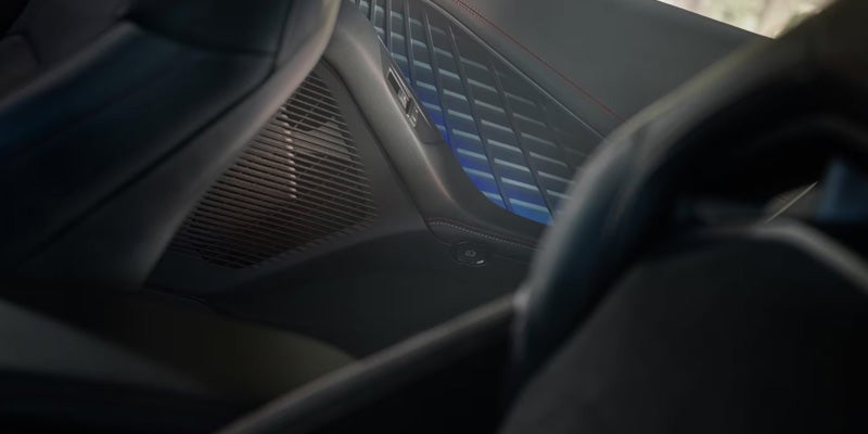 Close-up of a Dodge Charger Daytona door panel featuring blue ambient lighting, premium trim, and integrated speaker grille.