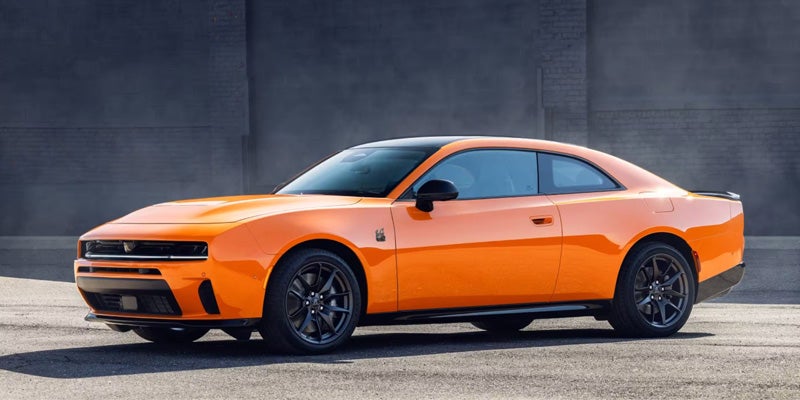 Orange Dodge Charger Daytona parked outdoors, displaying its full side profile, aerodynamic design, and performance styling.