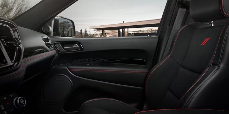 Front passenger area of the Dodge Durango featuring black leather seats with red accent stitching and premium interior trim.