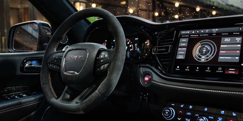 Driver-focused Dodge Durango cockpit featuring a leather-wrapped steering wheel, digital gauges, and an infotainment display.