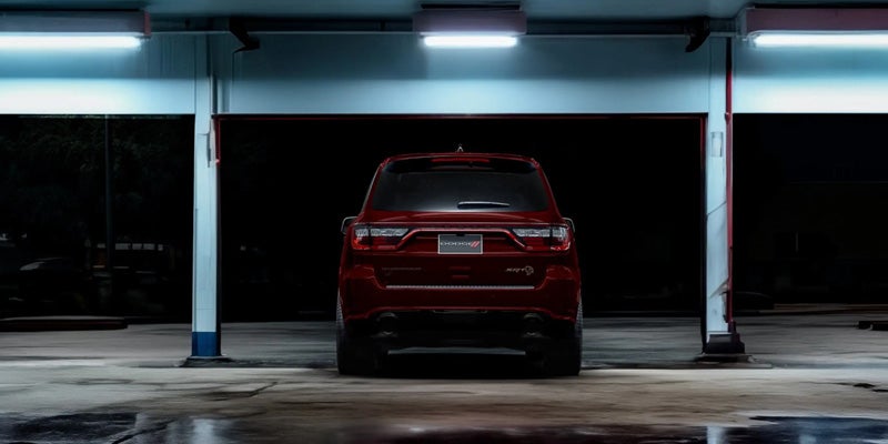 Rear view of a red Dodge Durango parked in a brightly lit garage, showcasing the full-width taillight design.