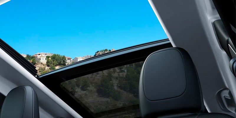 Jeep Cherokee interior featuring a panoramic sunroof with a clear view of the sky above the front seats.