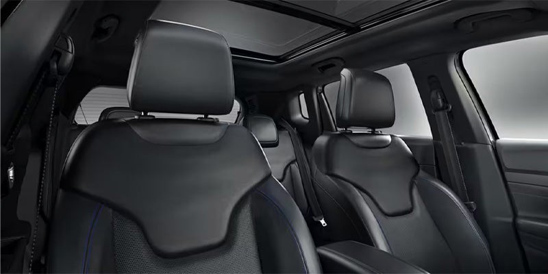 Interior of a car showing black leather seats with blue stitching and a sunroof.