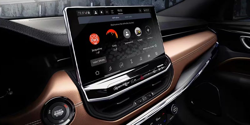 A car's dashboard with a large touchscreen showing user profiles and a "Start Engine Stop" button below.