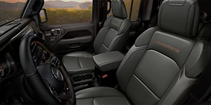 Interior of a dark grey Jeep Gladiator Mojave, showing the driver's side and passenger seat with "Mojave" embroidered.