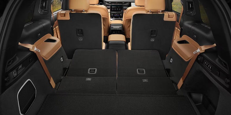 Cargo area of a car, showing the rear two rows of tan and black seats folded flat for maximum storage.
