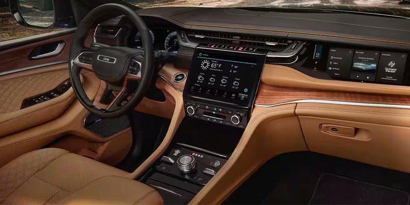 Luxurious light brown and dark brown Jeep Grand Cherokee interior, with a large central touchscreen display.