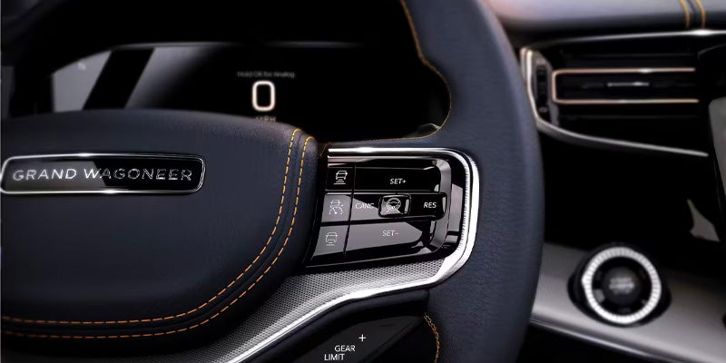 Close-up of a Grand Wagoneer steering wheel with control buttons and a digital display showing "0" in the background.