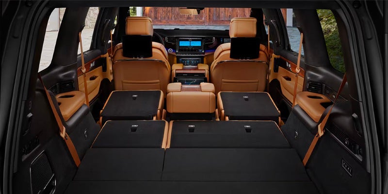 View from the back of a luxury SUV with the second and third-row seats folded flat to maximize cargo space.