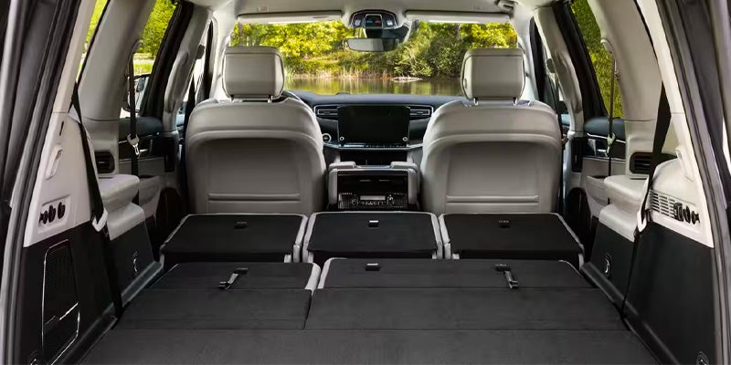 Rear view of a car interior with the back seats folded flat for cargo, revealing the front seats and dashboard.