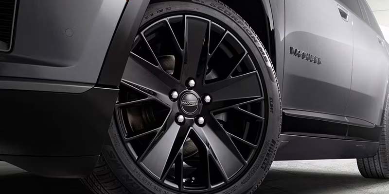 Close-up of a black Wagoneer SUV's front wheel with a black, multi-spoke rim and Pirelli Scorpion tire.