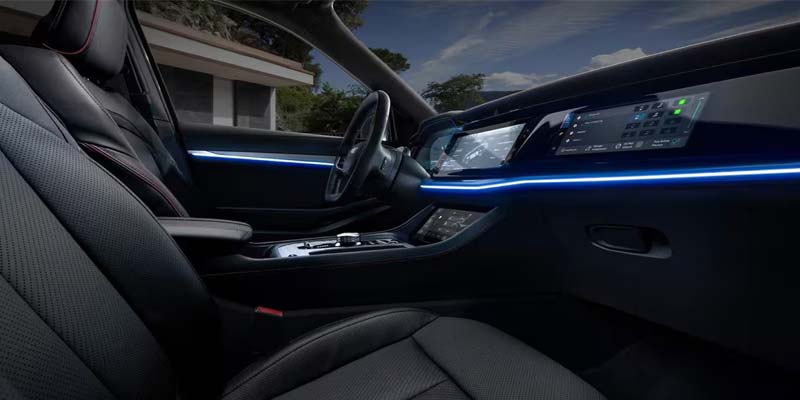 Interior of a car with black leather seats, illuminated blue accent lighting across the dashboard, and digital screens.
