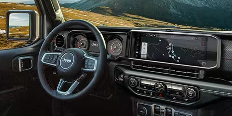Interior view of a Jeep with a large dashboard screen showing a map and controls, steering wheel visible.