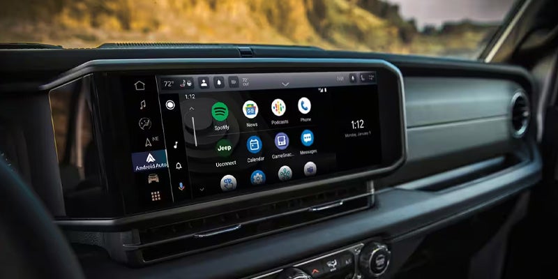 A large touchscreen display in a car's dashboard shows the Android Auto interface with various app icons.