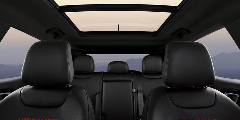 Jeep Compass interior featuring black leather seating and a large panoramic sunroof extending across the cabin.