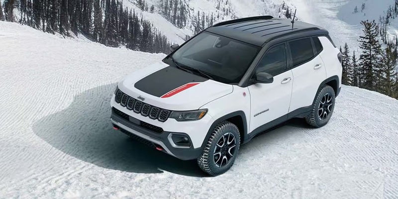 White Jeep Compass Trailhawk parked on a snow-covered mountain landscape, highlighting winter-driving capability