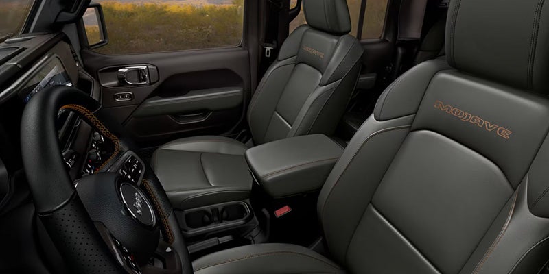 Front cabin of a Jeep Gladiator Mojave with black premium seats, contrast stitching, and embroidered Mojave branding.