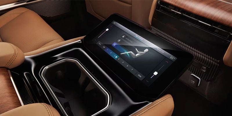 Rear center console touchscreen in a Jeep Wagoneer displaying climate and seat comfort controls beside dual cup holders.